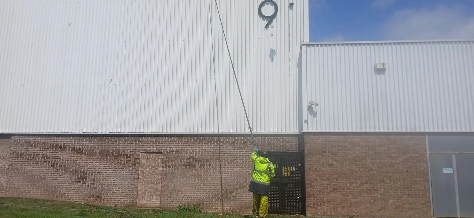 Warehouse cladding cleaning in progress with telescopic poles - wide angle view
