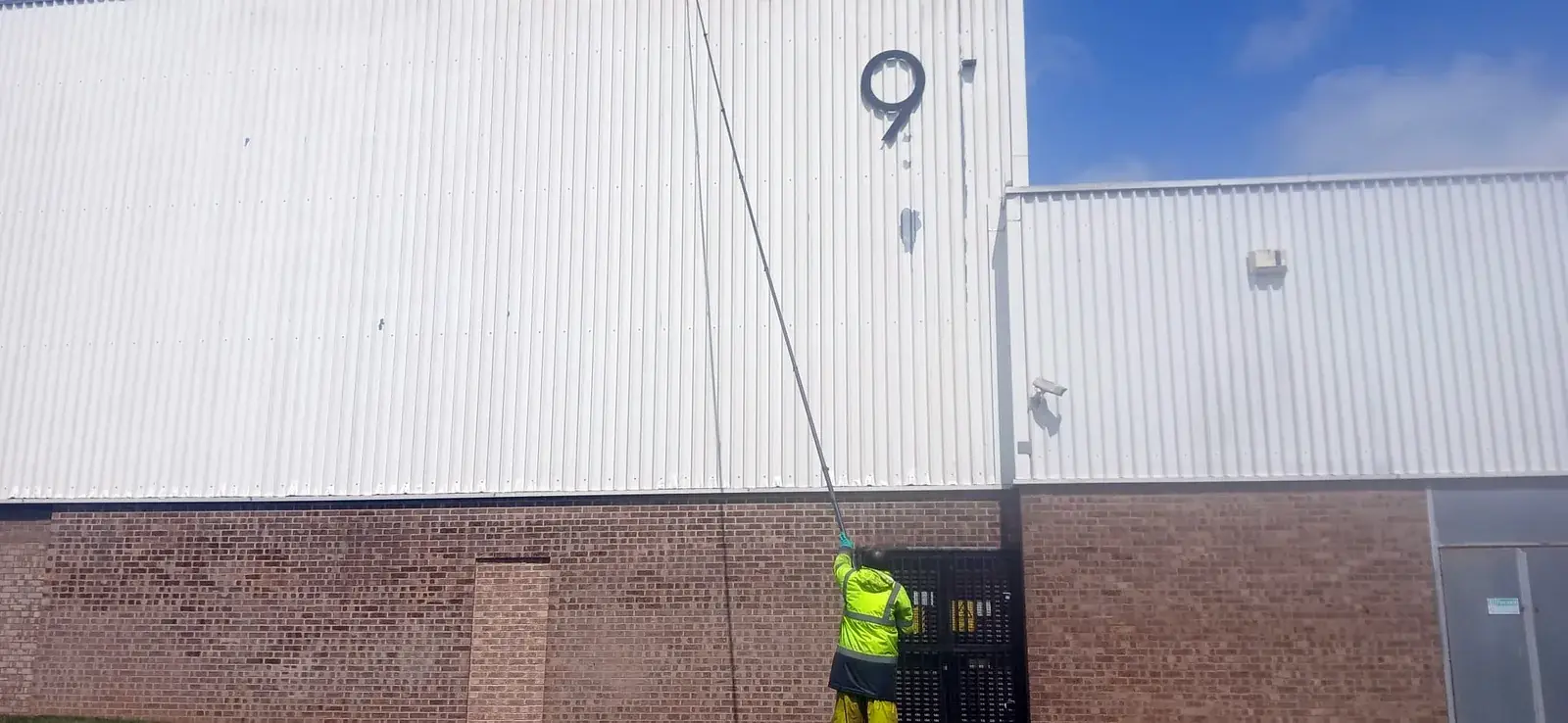 Technician cleaning warehouse cladding with extendable telescopic pole - AJB Group, Corby