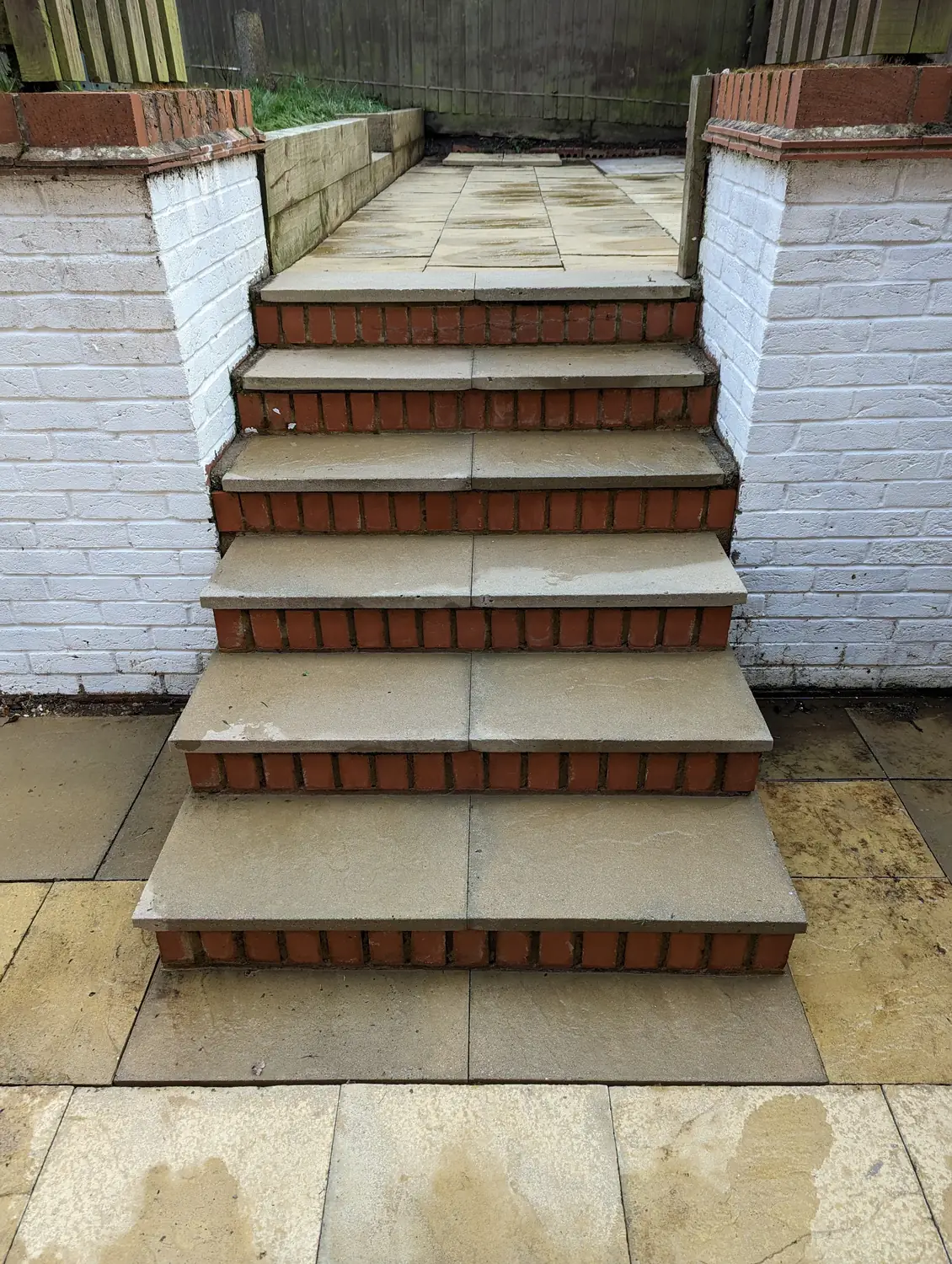 Stone slab garden steps with red brick risers between white-painted walls after professional cleaning