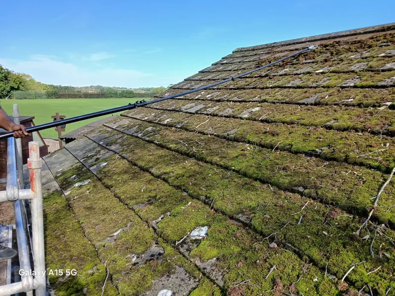 Thick moss growth covering concrete roof tiles before professional cleaning - showing how moss traps moisture against the roof surface