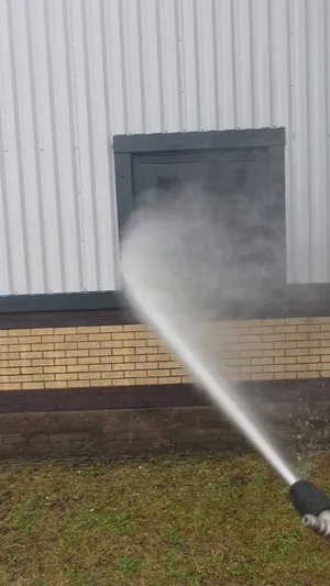 During - commercial building buff brick base pressure washed moss algae removal, Rugby.