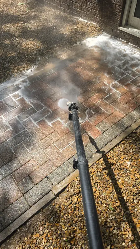 Brick paving path mid-clean - rotary surface cleaner pressure washing one section with a clear split between cleaned and dirty