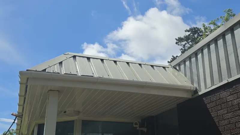 Entrance canopy cladding after soft washing - now a clean glossy cream-white finish under blue sky with scattered cloud