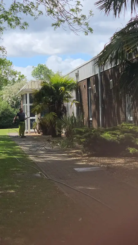 Distant view across lawn and palm tree to the Eurofins BLC main entrance with an operator handling hoses by the doorway