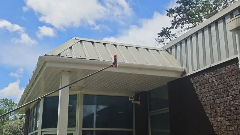 Telescopic pole with a red brush head completing finishing touches on the porch cladding underside
