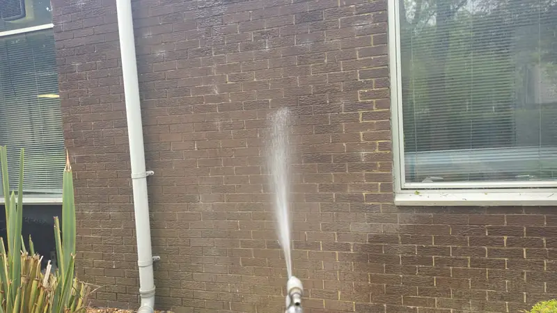 Soft wash solution visibly running down a wide brick wall panel during the treatment phase