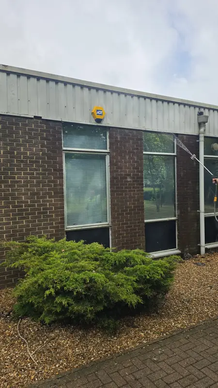 Window line on the side elevation being soft washed below the yellow ADT alarm signage with brick and cladding
