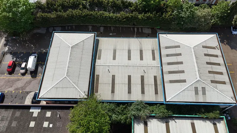 Aerial drone top-down view of three connected flat commercial roof zones with rectangular skylight panels