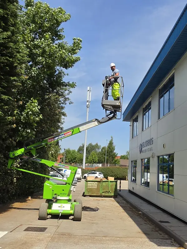 Wider view of the MEWP with boom fully extended and the operator at gutter level beside the two-storey Globus Medical corporate frontage