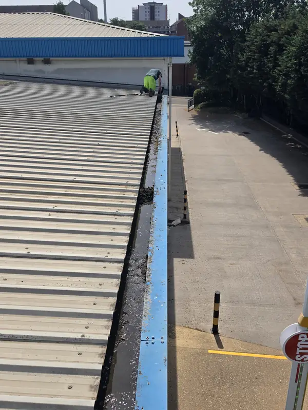 Operator in green hi-vis on the MEWP basket platform with metal safety rail in the foreground, STOP sign in the car park below
