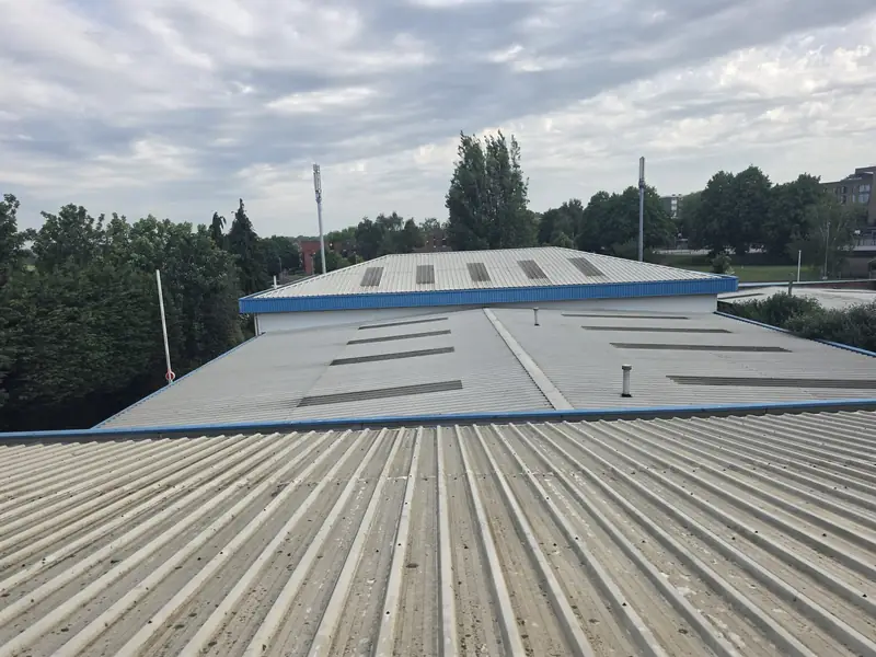 Operator-eye view from the ridge of the front bay across two more roof bays with four large skylight panels and blue capping