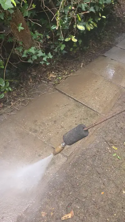 Natural stone patio slabs being jet washed, dirty-to-clean contrast - Luton