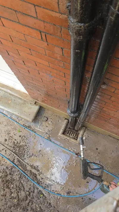 Downpipe and drain jetted clear at the base of a brick wall - Luton