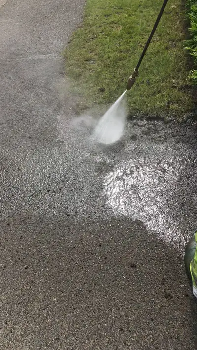 Tarmac driveway being jet washed, clear dirty-to-clean line - Orlingbury