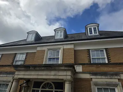 Wide view of the buff brick facade and slate dormer roof before cleaning - Orlingbury