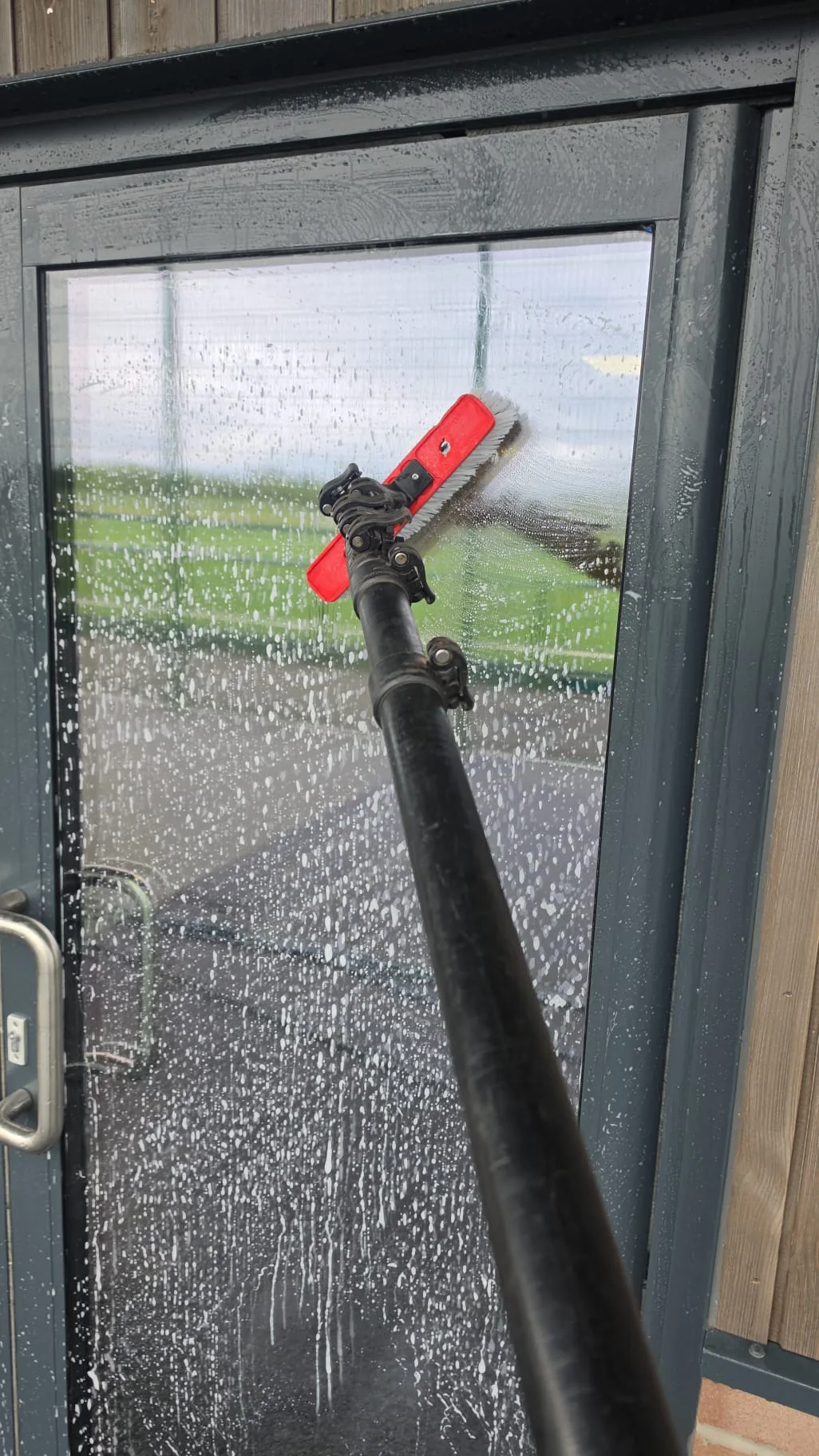 Water-fed pole brush working the glass door at The Phoenix Collegiate, West Bromwich