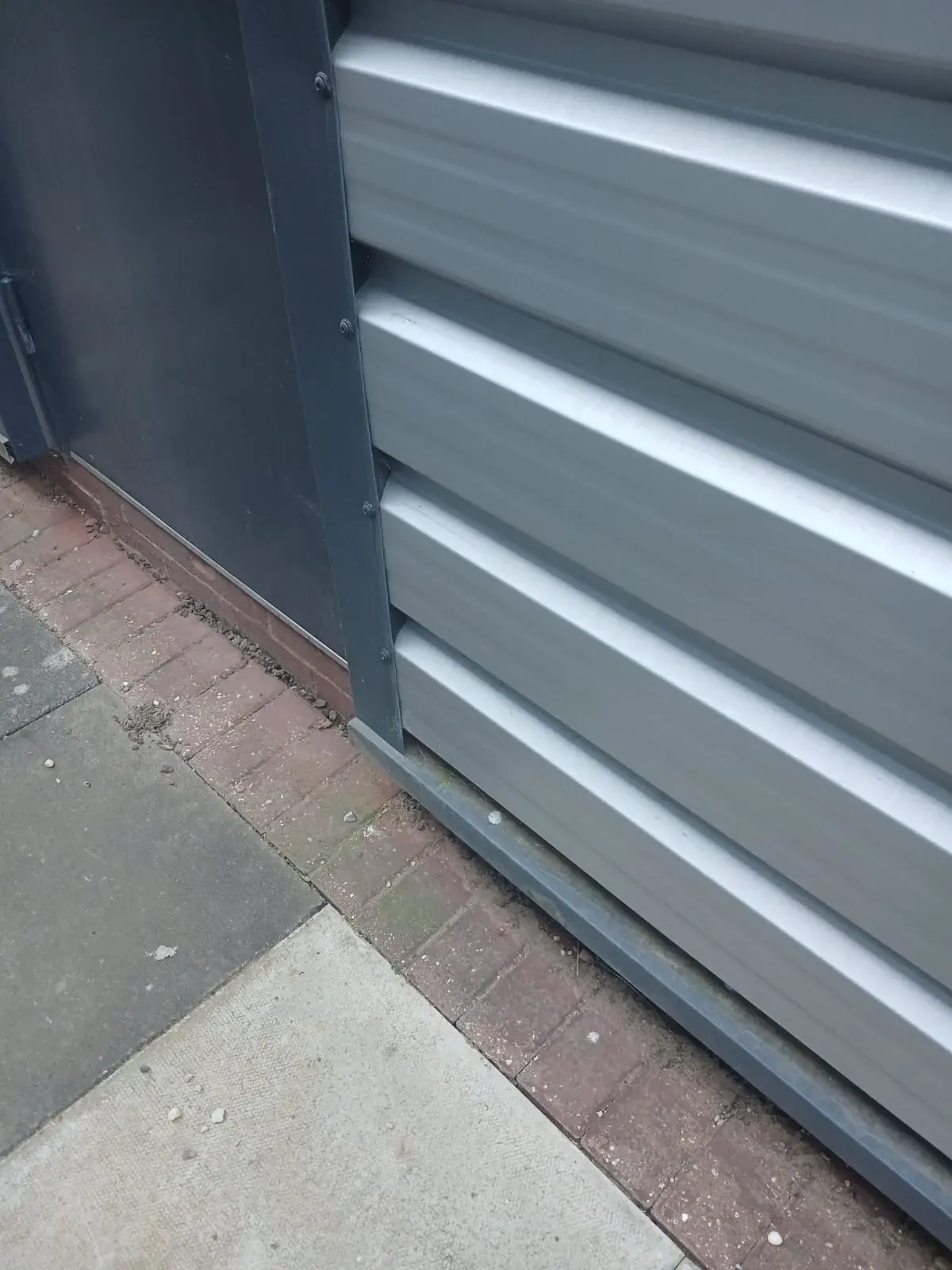 Commercial metal cladding before steam cleaning - algae and staining at base of wall, Dunstable