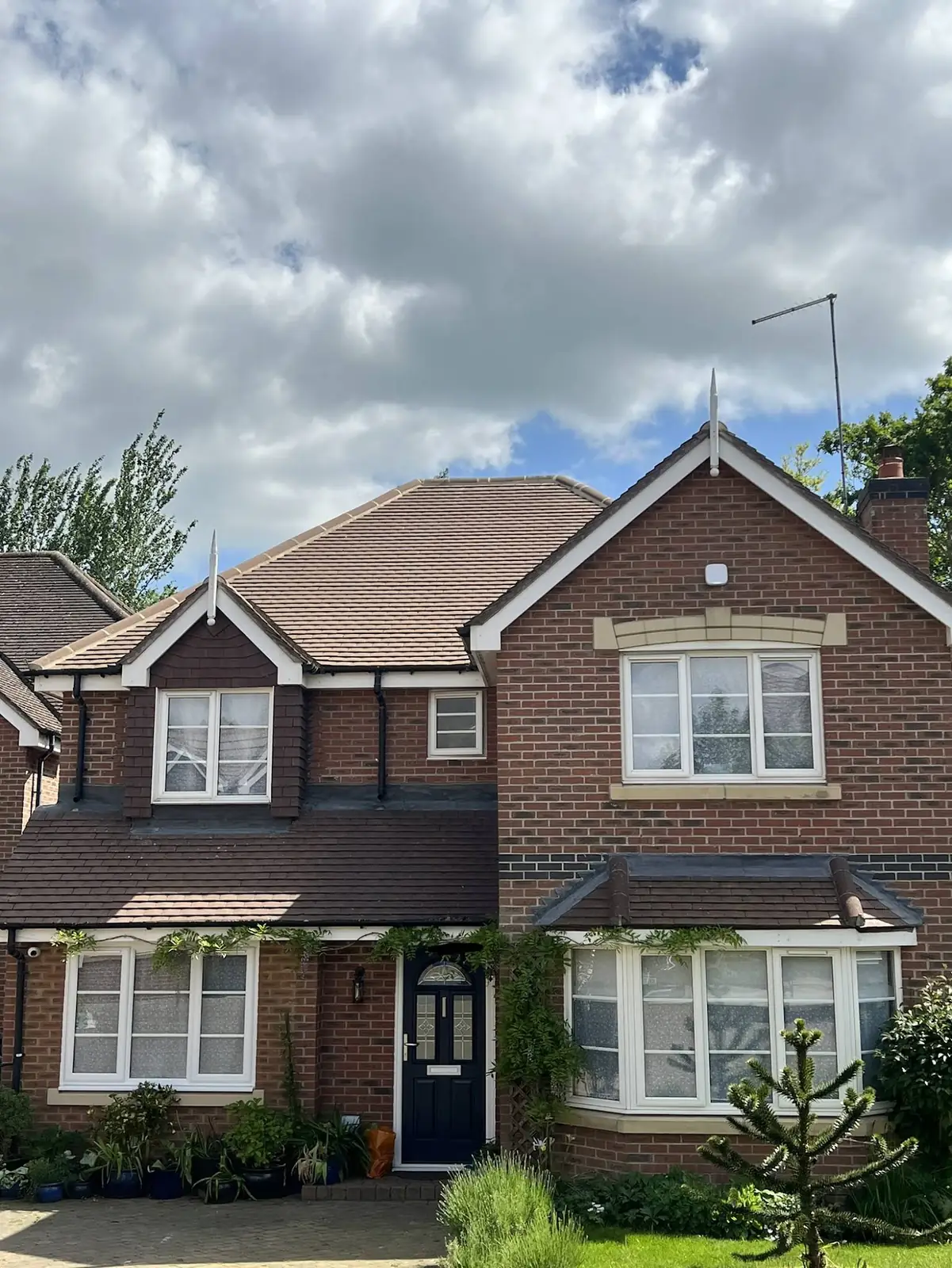 Detached brick house with a brown tile roof staying clean two years after professional roof treatment
